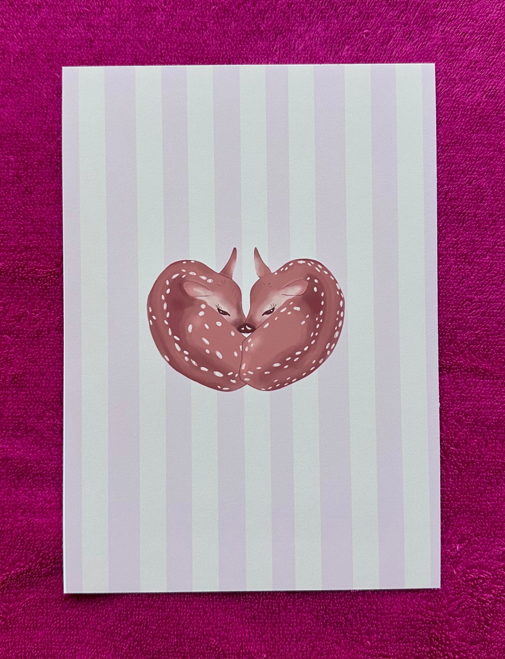Note card with a fawn illustration on a striped background, placed on a purple surface